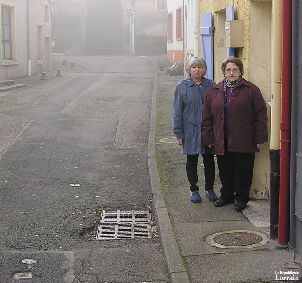 Mmes Lucette Zdun et Mathilde Pilla née Becker, deux des rescapées devant les lieux où se déroula le drame, il y a 64 ans. En bas à gauche, les petits « couvercles » de la conduite de gaz. (photo DR)