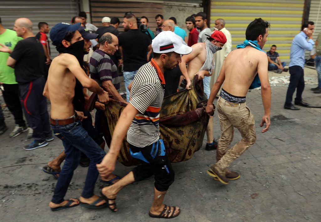 Iraqis evacuate a body from the site of a suicide car bombing claimed by the Islamic State group on July 3, 2016 in Baghdad's central Karrada district. The blast, which ripped through a street in the Karrada area where many people go to shop ahead of the holiday marking the end of the Muslim fasting month of Ramadan, killed at least 75 people and also wounded more than 130 people, security and medical officials said. The Islamic State group issued a statement claiming the suicide car bombing, saying it was carried out by an Iraqi as part of the group's "ongoing security operations". / AFP / SABAH ARAR