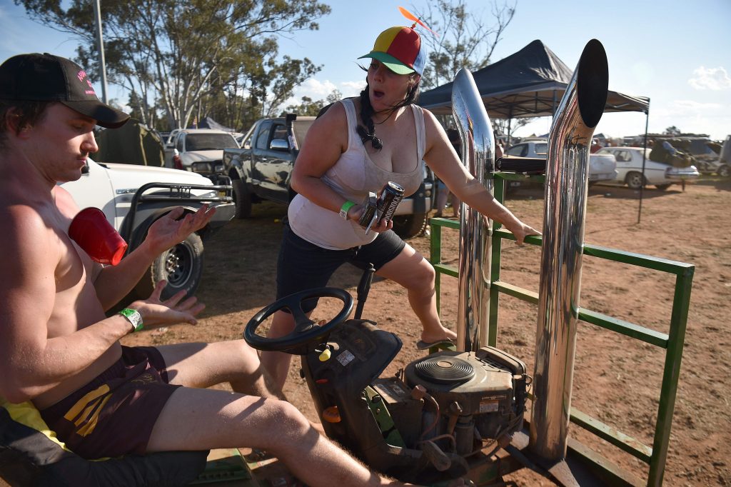 This photo taken on October 29, 2016 shows a participant getting on a tractor before a "Bachelor and Spinster" ball in the town of Ariah Park in western New South Wales.  Pick-up trucks, cowboy boots and a 24-hour booze-fuelled party in the Outback: welcome to modern-day dating in Australia's bush, where swiping right is not an option. - TO GO WITH Australia lifestyle social dating, FEATURE by Glenda KWEK   / AFP / Peter PARKS / TO GO WITH Australia lifestyle social dating, FEATURE by Glenda KWEK