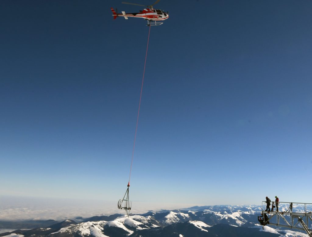 A helicopter is used during the installation of a 12-meter-long platform at the top of the Pic du Midi, one of France's tallest mountains, in Bagneres-de-Bigorre on January 30, 2018. / AFP PHOTO / PASCAL PAVANI